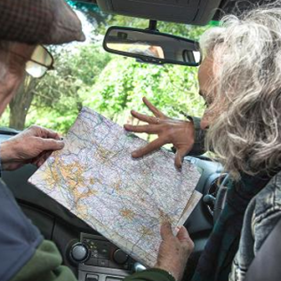 elderly couple reading a map inside rental vehicle