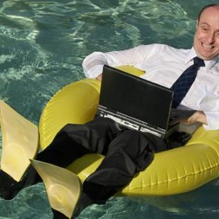 Business man on pool float in water working on laptop