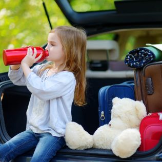 Child sitting in rental vehicle drinking bottle of water
