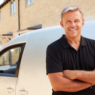 Man smiling leaning up against commercial van